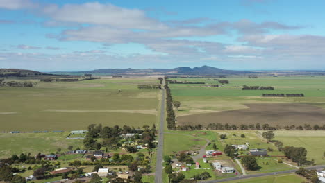 aerial long straight road heading out of small rural township