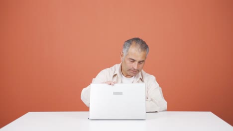 hombre cerrando la computadora portátil con expresión de enojo.