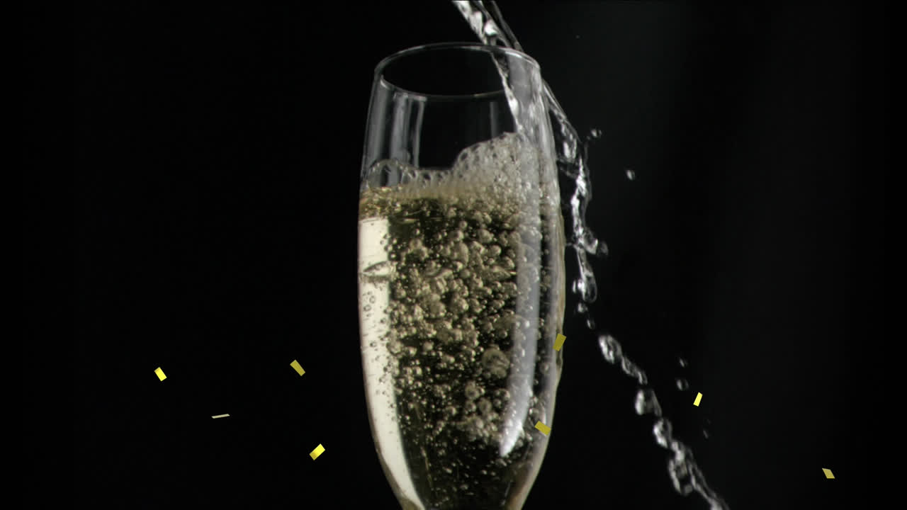 검은색 배경에 페인 유리잔 위에 떨어지는 금색 콘페티의 애니메이션