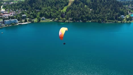 Aerial-View-Of-Paraglider-Soaring-Above-Waters-Of-Lake-Bled-In-Slovenia