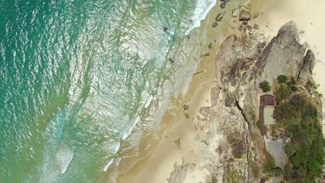 rocky headland ,crystal clear water, small waves, from the vertical , drone shot holding still for wonderful footage