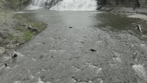 A-low-drone-shot,-revealing-a-big-waterfall-by-moving-forward-and-panning-up