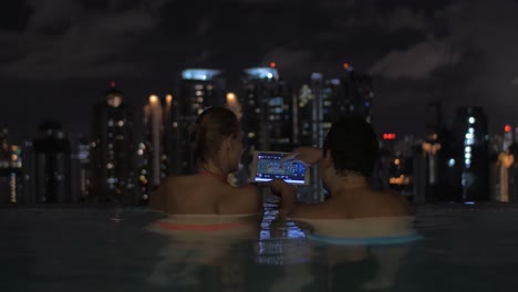 couple with pad in rooftop pool of night kuala lumpur