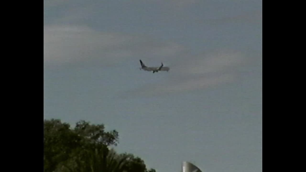 Airplane flying in the sky over trees in VHS frame