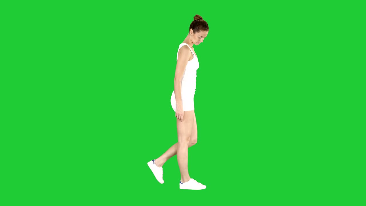 Young woman in sportswear taking a walk looking down on a Green Screen, Chroma Key
