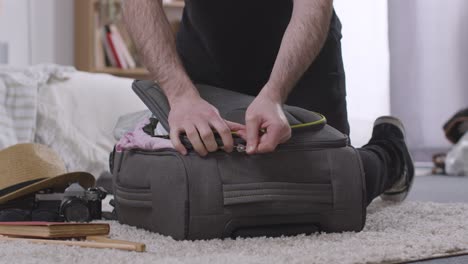 hombre luchando para empacar una maleta llena en el dormitorio en casa para las vacaciones de verano 1