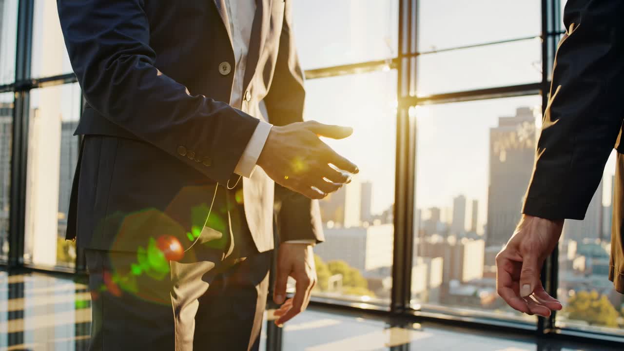 Low-angle video shot of two business professionals shaking hands in a modern office with cityscape