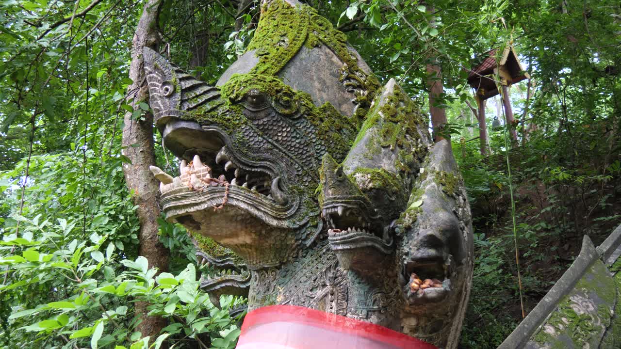 Mossy Naga serpent statue in jungle at Wat Umong temple, Chiang Mai, Thailand