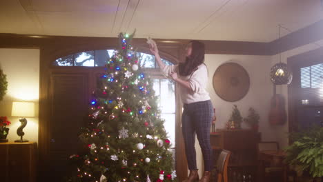 woman decorating a christmas tree with a star topper