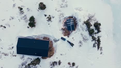 above view of a cabin surrounded by snow in winter mountains