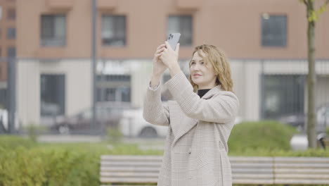 woman taking a photo in city park