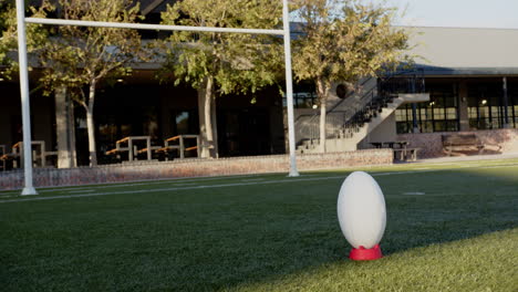 rugby ball on tee in outdoor field, ready for kick-off during practice, copy space