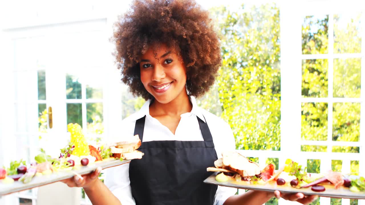Portrait d'une serveuse souriante tenant un plateau repas
