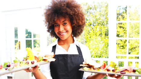 Portrait-of-smiling-waitress-holding-food-tray