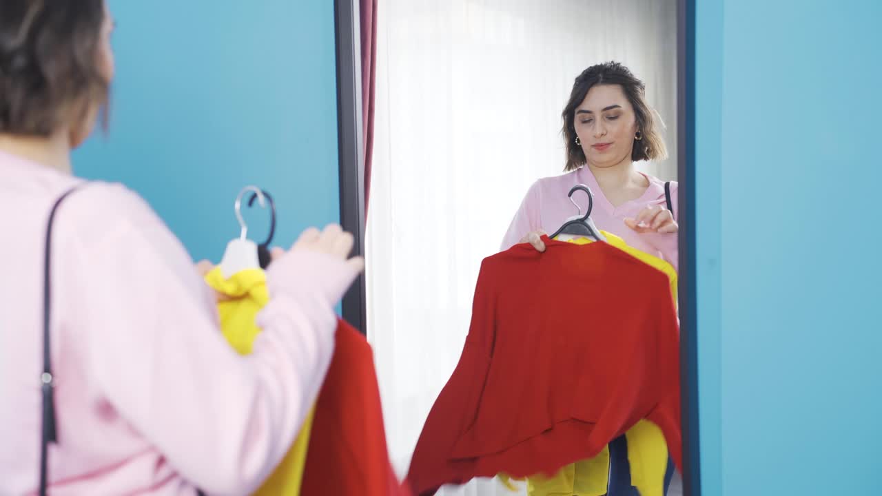 mujer joven tratando de decidir mientras lleva la ropa.