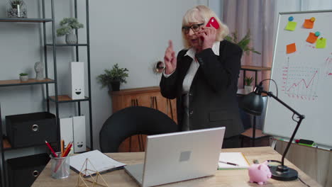 mujer de negocios senior enojada haciendo una llamada telefónica en la oficina trabajo molesto jefe hablando mobile pelea