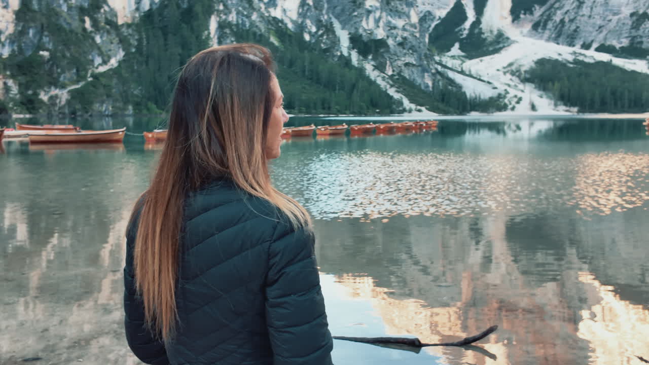 Mature woman enjoying breathtaking view of Lago di Braies and surrounding mountains in the Dolomites, Italy