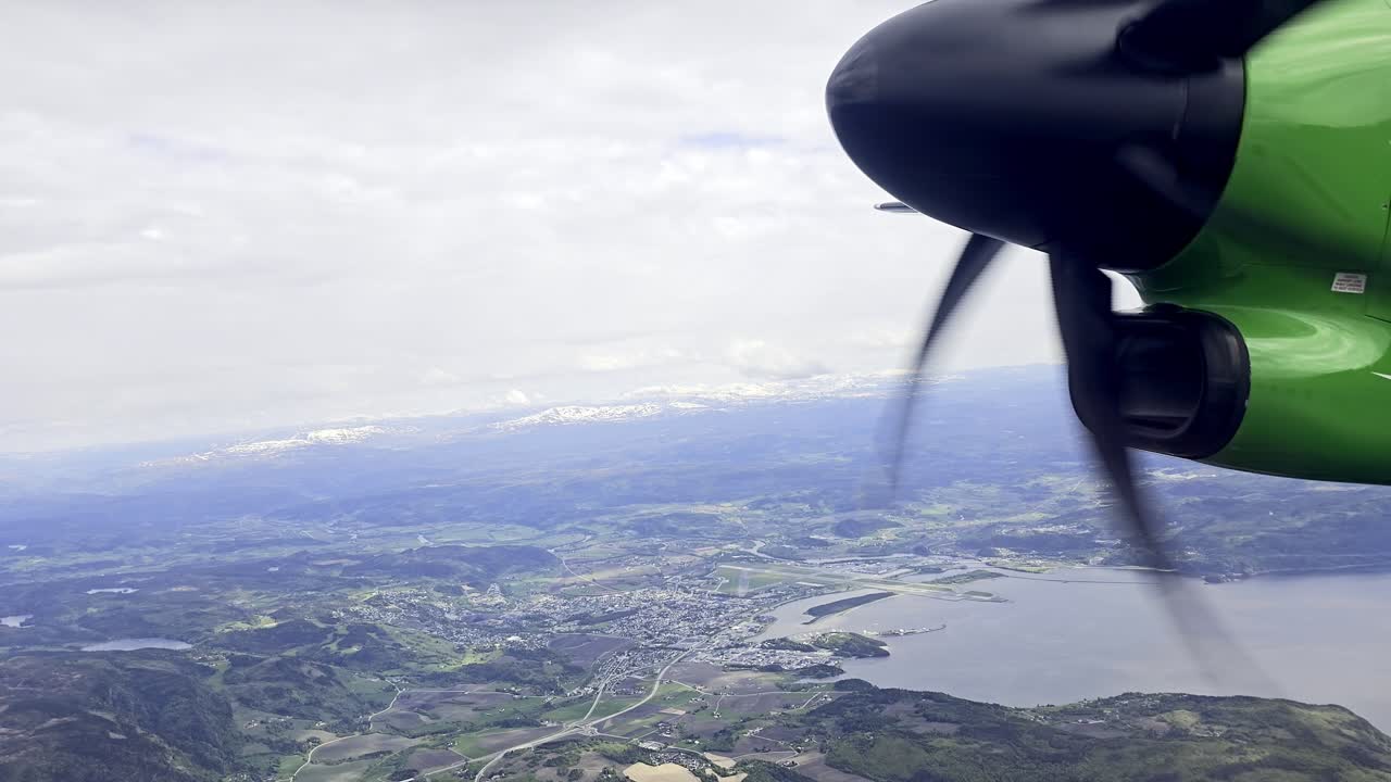 View from passenger window as small propeller plane cruises over Norway rural terrain