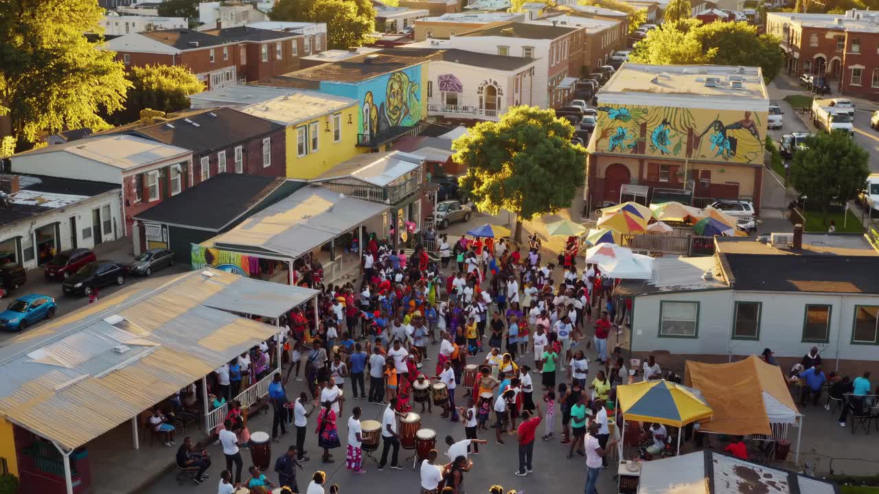 Vista aérea de un vibrante festival callejero con murales coloridos y carpas.