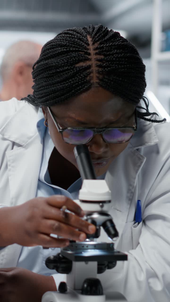 Video verticale. Scienziata che utilizza un microscopio ottico per studiare microrganismi in laboratorio
