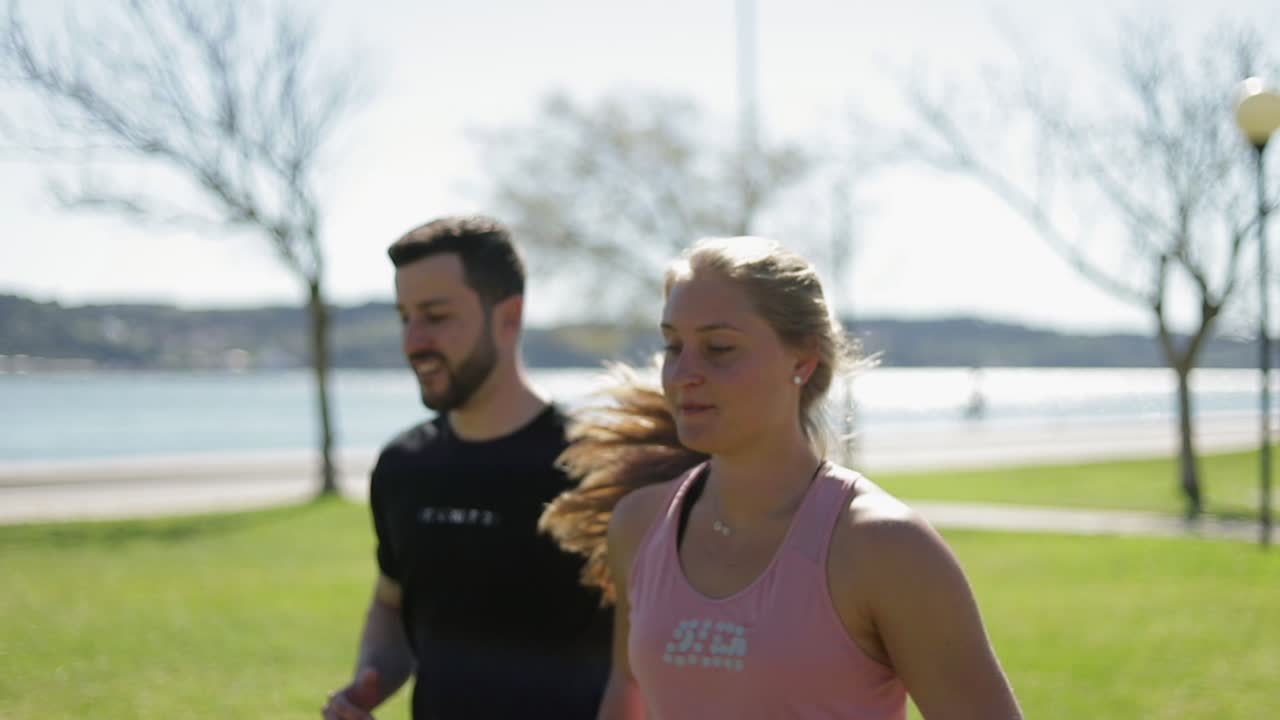 jóvenes deportivos corriendo en el parque cerca del terraplén.
