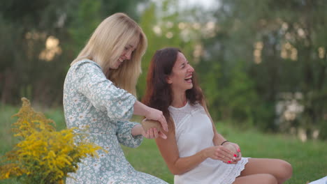 laughing young women sculpt clay products in nature in the park in the open space. group creative classes women's circle communication humor fun spending time together.