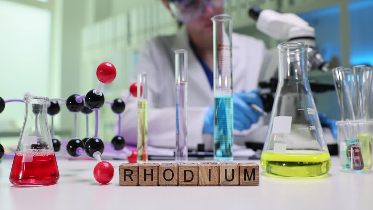 Wooden cubes spell word rhodium on laboratory table by scientist