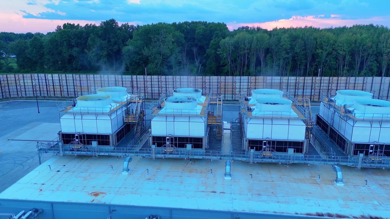 Large cooling units on the roof of a data center emitting steam during a colorful sunset in Ohio