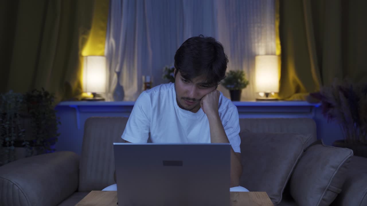 Unhappy man using laptop laptop at night. It's not in a good mood.