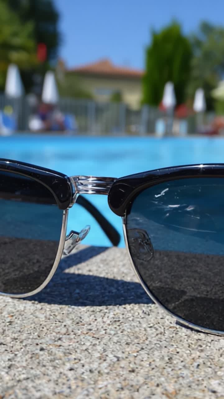 Stilige solbriller som hviler ved et forfriskende basseng, som fremhever en avslappende utendørs atmosfære perfekt for fritid og sommeraktiviteter.