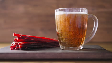 dried salmon sticks and fresh beer on wooden board in pub