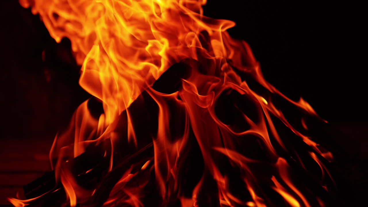 Wood stacked in a pyramid burn in the campfire. Isolated bonfire on the black backdrop. Close up.
