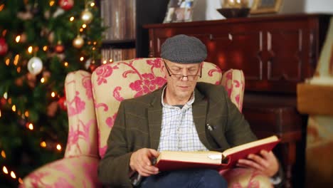 a senior man is reading a festive christmas story from a large red book