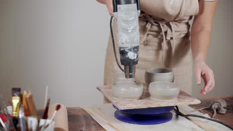woman making pottery with hot air gun
