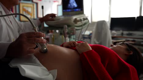 gynecologist scanning the belly of his pregnant patient with ultrasound