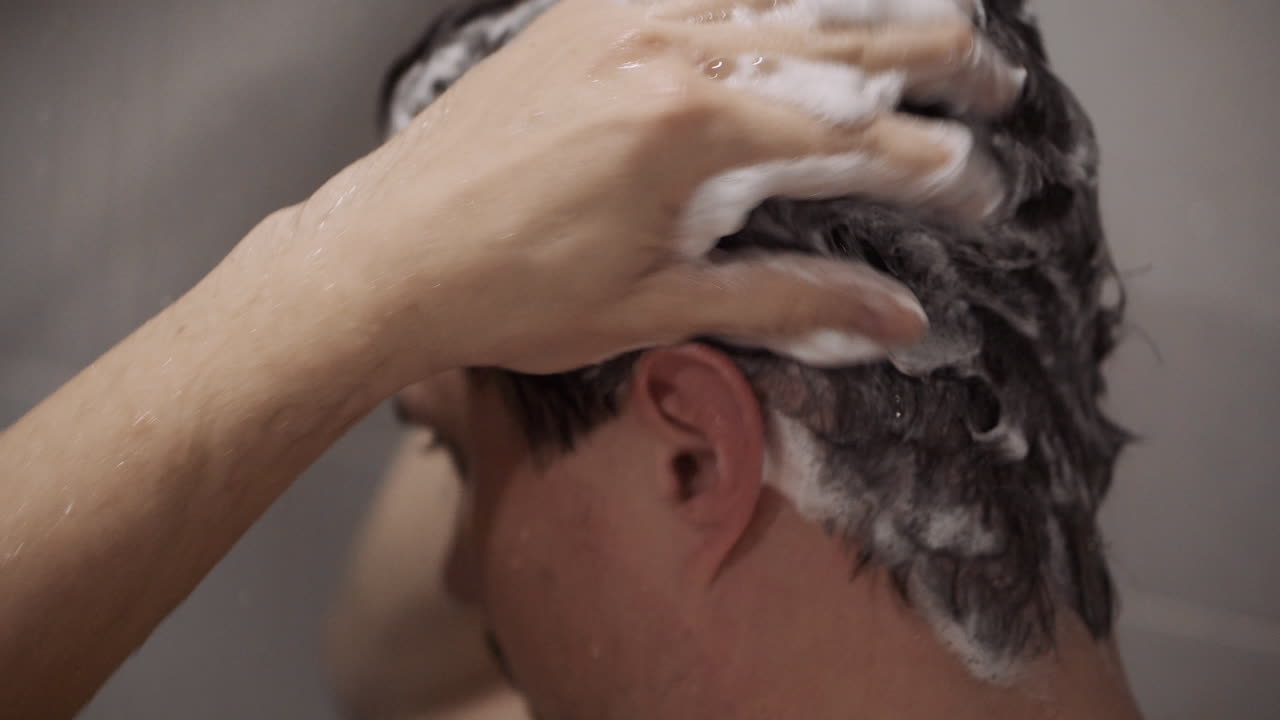 Uomo che si lava i capelli sotto la doccia