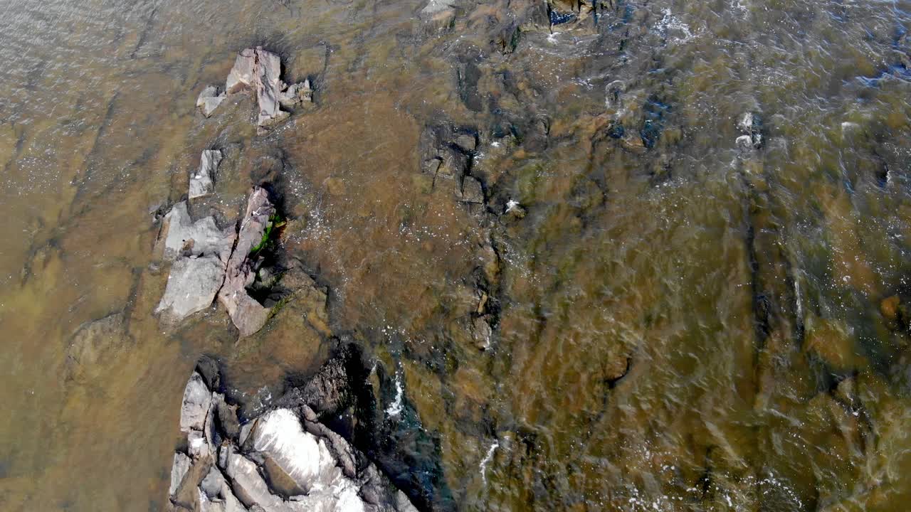 vista aérea vertical de piedras en el mar con olas rompiendo en el muelle, montevideo, uruguay