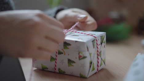 hände binden band um ein verpacktes weihnachtsgeschenk, nahaufnahme