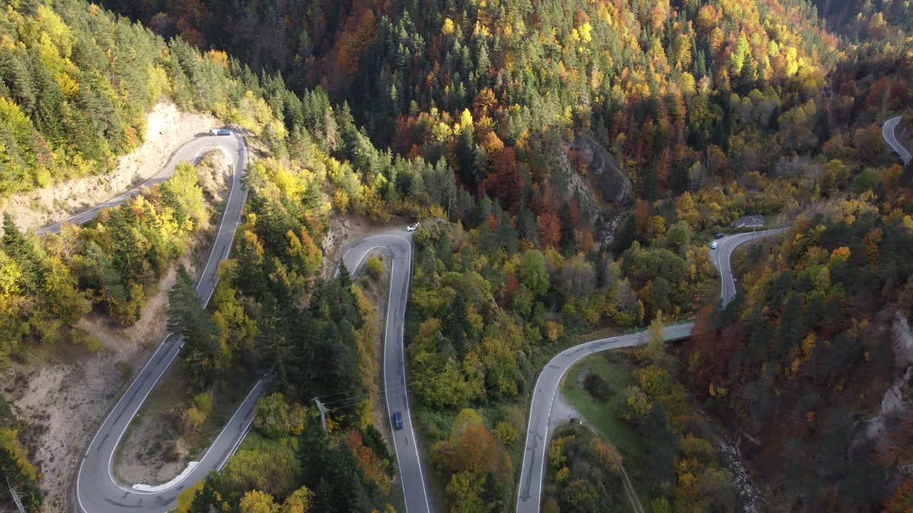 imágenes aéreas sobre automóviles de los pirineos conduciendo por el bosque de paso alto de montaña en otoño en el norte de españa durante una hermosa puesta de sol