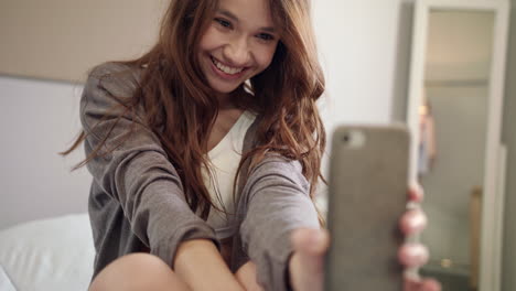 mujer joven tomando una foto selfie en el teléfono móvil en el dormitorio