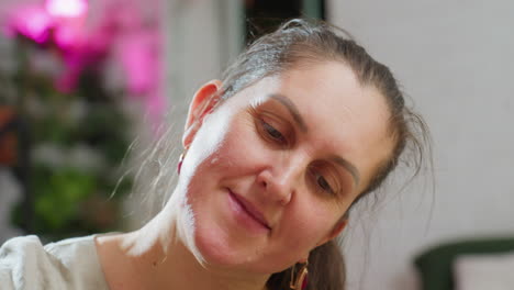 portrait view of woman looking determined while focusing on task, with blurred festive background, soft colorful lights, and cozy indoor atmosphere creating warm holiday spirit in peaceful home