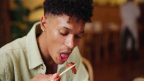 man eating with chopsticks in a restaurant
