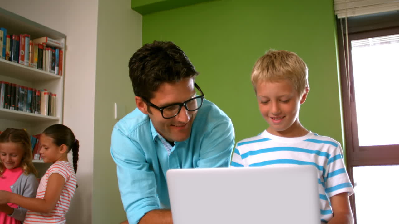 maestro y escolar usando computadora portátil en la biblioteca