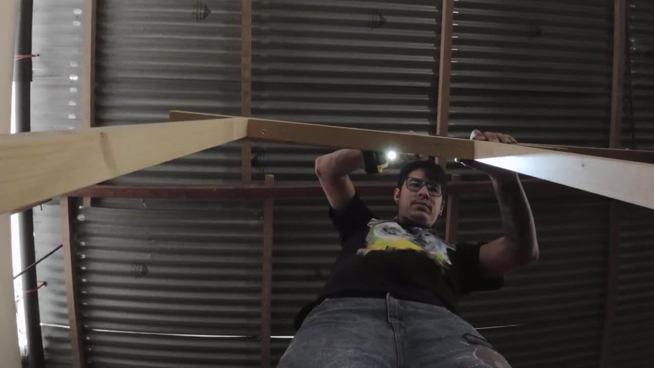 Uomo che fora una trave di legno in officina