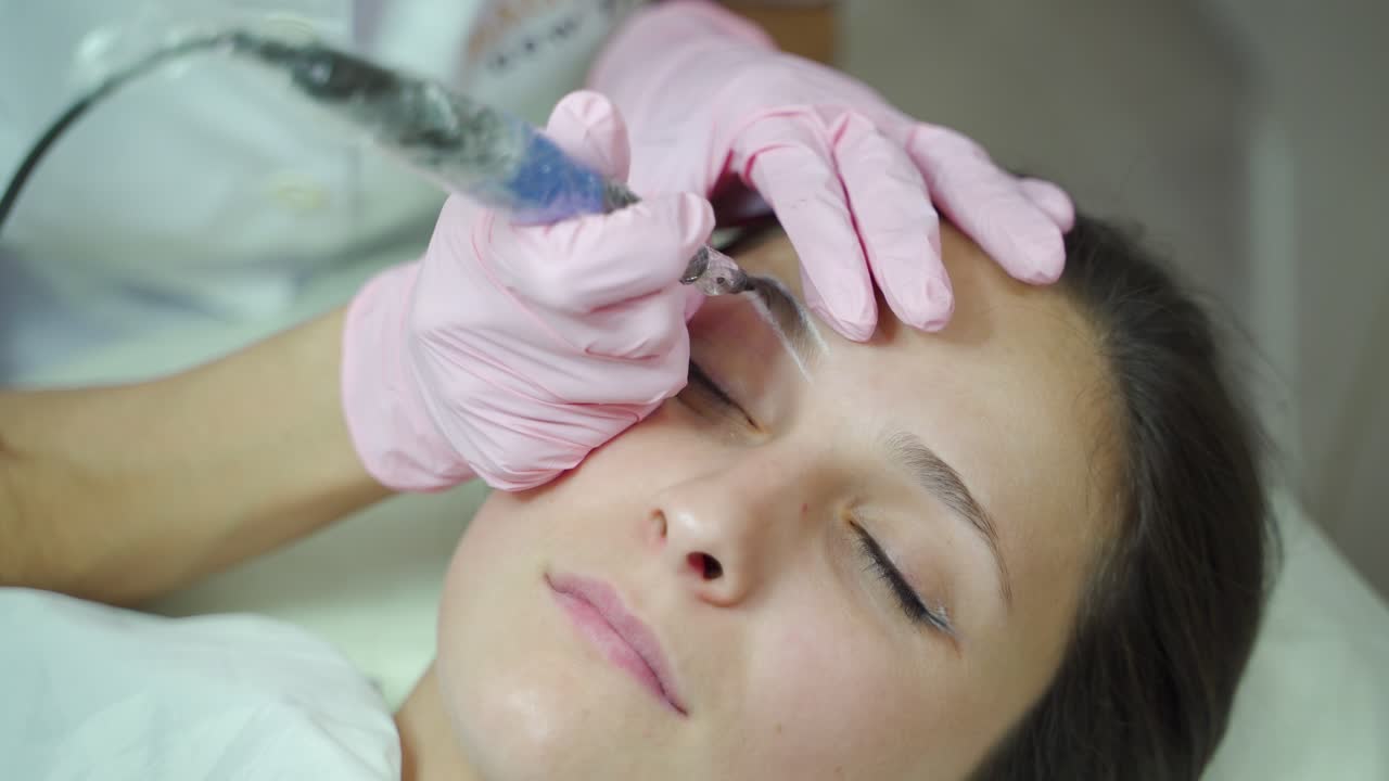 cosmetologist is performing a permanent eyebrow makeup procedure for the client. Modern cosmetology