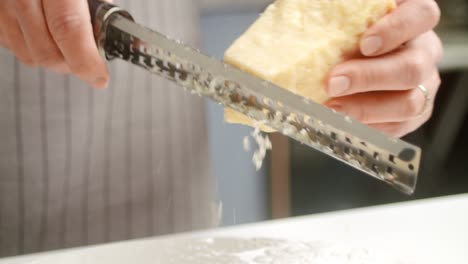 crop cook grating parmesan cheese on plate with risotto