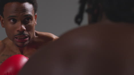 close up studio shot of two male boxers wearing gloves fighting in boxing match against grey background 11