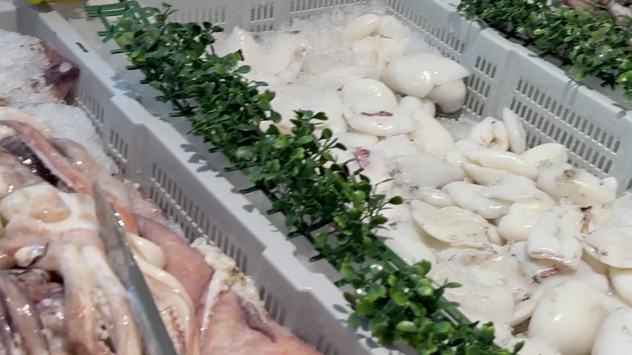 Close-up view of cuttlefish and squid on ice, garnished with fresh parsley.