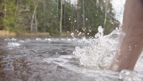 slow motion - bare feet smash through the ice to enter the lake for bathing