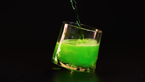 green liquid poured into tilted glass, creating bubbles